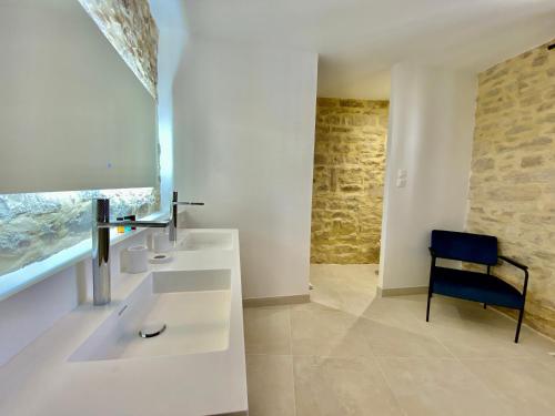 a bathroom with two sinks and a blue chair at La Maison des Vendangeurs - TABLE D'HÔTES le soir du jeudi au dimanche- Jacuzzi - Balnéo SPA - ACCES PISCINE pour toutes les chambres sauf STUDIO COQUET- Piscine de mai à mi-octobre in Martignargues