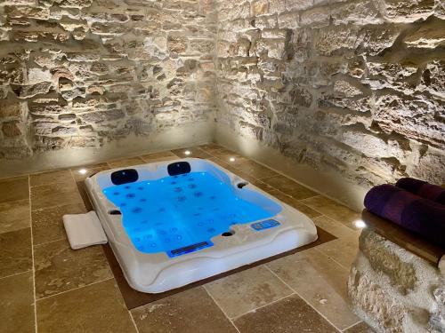 a bath tub in a room with a stone wall at La Maison des Vendangeurs - TABLE D'HÔTES le soir du jeudi au dimanche- Jacuzzi - Balnéo SPA - ACCES PISCINE pour toutes les chambres sauf STUDIO COQUET- Piscine de mai à mi-octobre in Martignargues