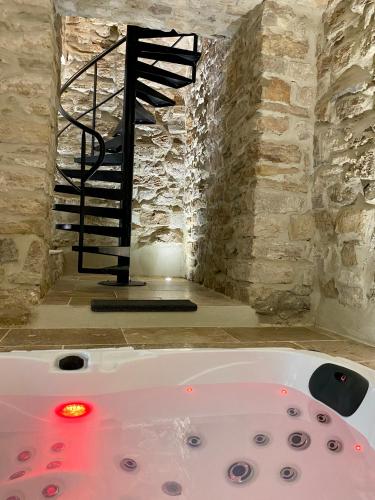 a bath tub in a room with a staircase at La Maison des Vendangeurs - TABLE D'HÔTES le soir du jeudi au dimanche- Jacuzzi - Balnéo SPA - ACCES PISCINE pour toutes les chambres sauf STUDIO COQUET- Piscine de mai à mi-octobre in Martignargues
