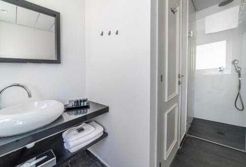 a white bathroom with a sink and a mirror at Dizengoff Avenue Boutique Hotel in Tel Aviv
