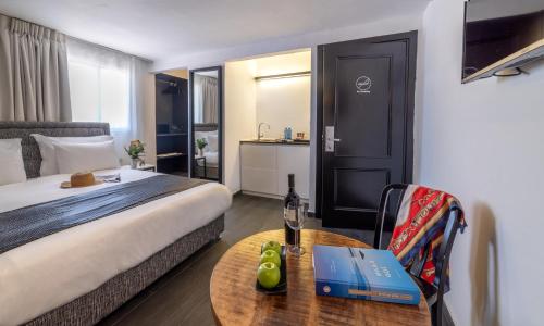 a hotel room with a bed and a table with a book at Dizengoff Avenue Boutique Hotel in Tel Aviv