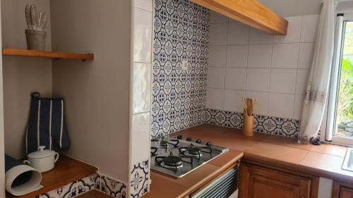 a kitchen with a stove top oven next to a window at Casa da Avó Duca in Machico