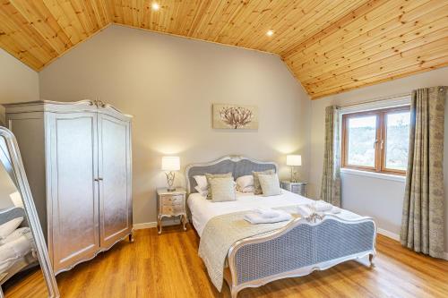 a bedroom with a bed and a wooden ceiling at Thistle Lodge 18 with Hot Tub in Belladrum