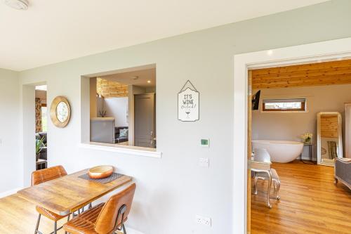 a dining room with a table and a bath tub at Thistle Lodge 18 with Hot Tub in Belladrum