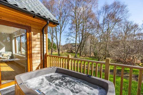 a hot tub on the porch of a house at Thistle Lodge 18 with Hot Tub in Belladrum