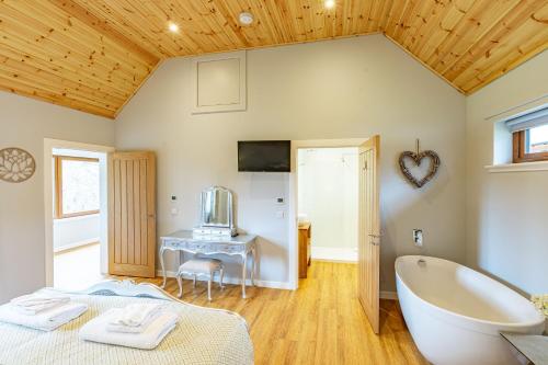 a bathroom with a tub and a bed and a sink at Thistle Lodge 18 with Hot Tub in Belladrum