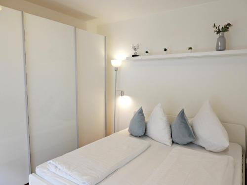 a bedroom with a white bed with blue and white pillows at Braviscasa - Ferienresidenz Stadttor Endingen in Endingen