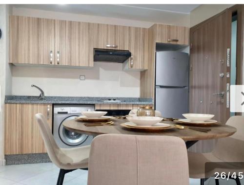een keuken met een tafel met stoelen en een koelkast bij Oceanica by Smir Park luxury apartment Marina Smir in M'diq