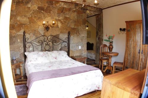 1 dormitorio con cama y pared de piedra en Pousada Toque Mineiro, en Tiradentes