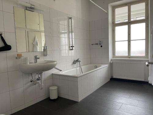 a white bathroom with a sink and a bath tub at Apartments am Bodensee in Bregenz