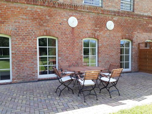 a table and chairs in front of a brick building at Gut Vorwerk in Sagard