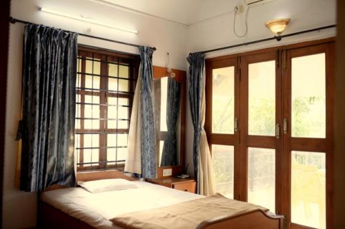 a bedroom with a bed and a large window at Anna's Bungalow 4BHK in Alibaug