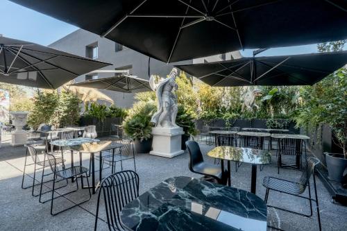 a patio with tables and chairs and a statue at Collini Rooms in Milan