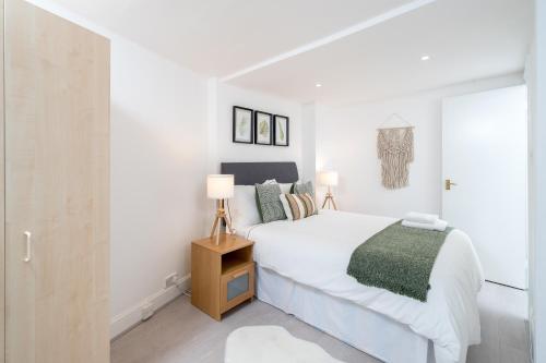 a white bedroom with a bed and two lamps at Russell Sq Suite - 2 Bed Apartment in London