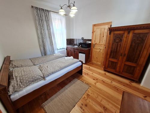 1 dormitorio con cama, ventana y suelo de madera en Apartmány Perla, en Banská Štiavnica
