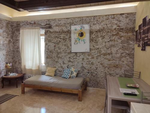 sala de estar con sofá y pared de piedra en Il giardino dei semplici B&B, en Caulonia