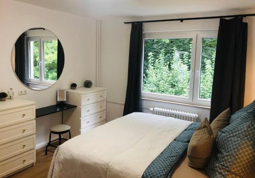 een slaapkamer met een bed en een bureau en twee ramen bij Apartment am Kurpark in Wilhelmshaven