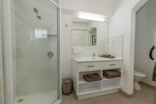 baño blanco con ducha y lavamanos en Barclay Motor Inn en Devonport