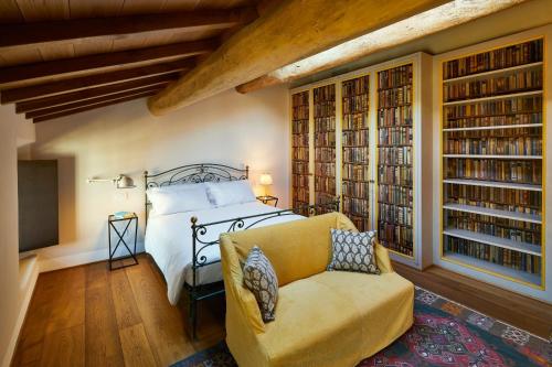 a bedroom with a bed and a chair and bookshelves at Casa Gugù in Ravenna