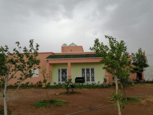 a pink and white house with trees in front of it at Almaqussoura in Marrakesh