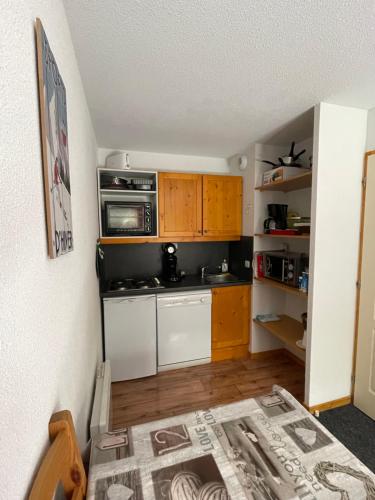 une petite cuisine avec une cuisinière et un micro-ondes dans l'établissement Le ValmySki, à Valmeinier
