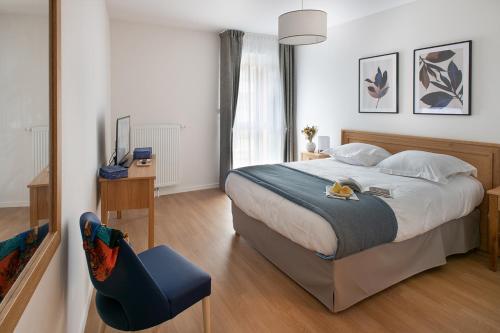 una camera con un grande letto e una sedia blu di Domitys Les Houblons a Brest