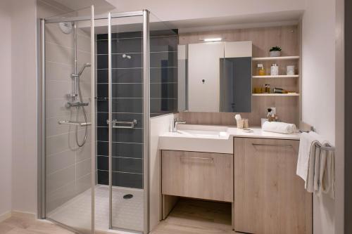 La salle de bains est pourvue d'une douche et d'un lavabo. dans l'établissement Domitys Les Houblons, à Brest