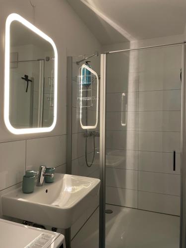 a white bathroom with a sink and a shower at Emerald Green Apartment in Offenbach