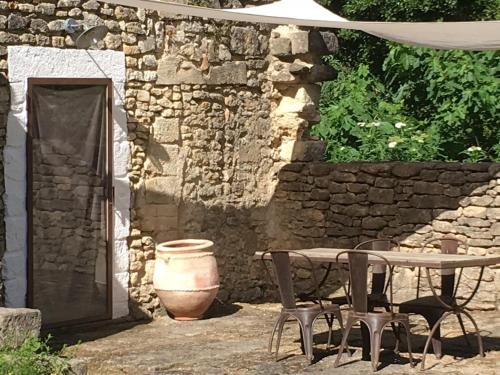 a table and chairs in front of a stone building at Uzes, loft dans Moulin independant 18e siecle en bord de riviere piscine privee 15x3 in Uzès