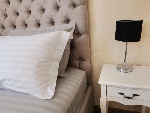 a bed with a white pillow and a lamp on a side table at Kavaler inn hotel in Kuty