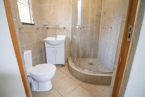 La salle de bains est pourvue de toilettes, d'une douche et d'un lavabo. dans l'établissement BON Hotel Rustenburg, à Rustenburg