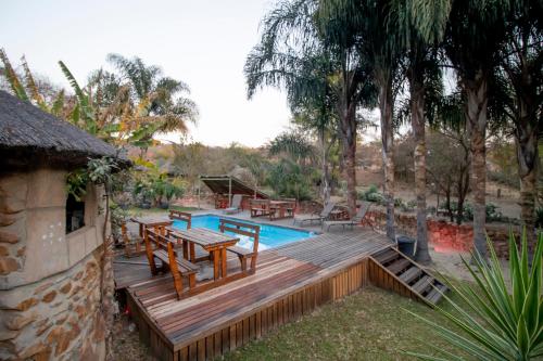a deck with a table and benches next to a pool at BON Hotel Rustenburg in Rustenburg