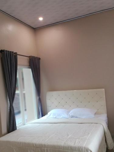 a bedroom with a white bed with a window at VILLA PRINGGITAN in Karanganyar