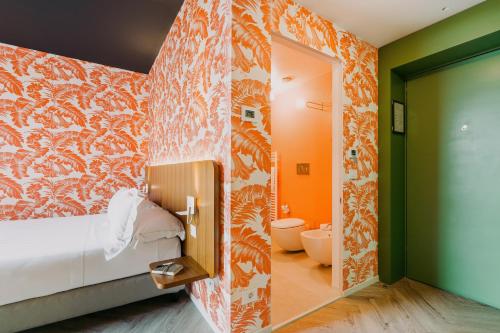 a bedroom with an orange and white wall at Collini Rooms, WorldHotels Crafted in Milan