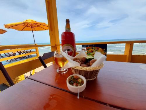 a table with a bottle of beer and a basket of food at VILLA COIMBRA in Lauro de Freitas