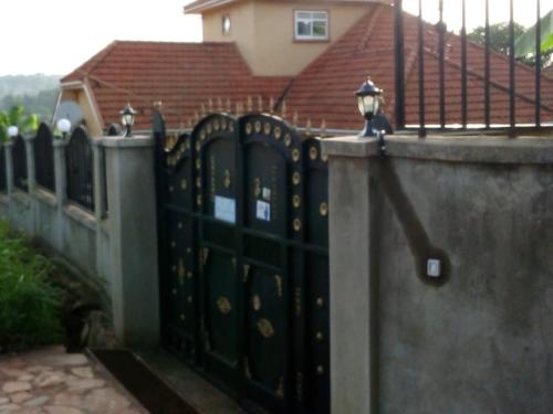 a fence with a black gate in front of a house at Captivating 3-Bed Villa in Bwebajja