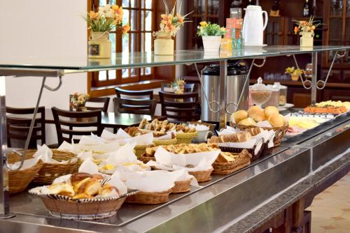uma linha de buffet com cestas de pão e pastelaria em Pousada Appaloosa em Águas de Lindoia