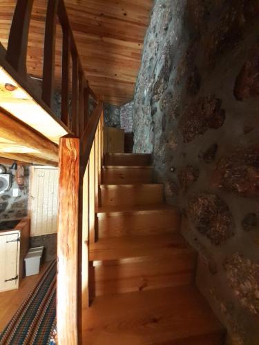 a staircase in a cabin with wooden floors and a stone wall at Casa Encantada - Alvoco da Serra in Alvoco da Serra