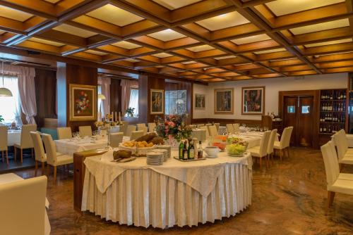 une salle à manger avec des tables et des chaises blanches ainsi qu'une table avec de la nourriture dans l'établissement Hotel Alla Posta, à Alleghe