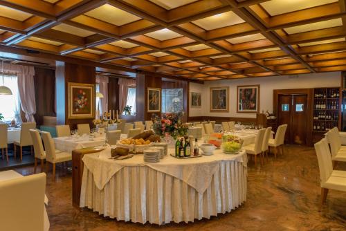 a dining room with white tables and chairs and a table set with food at Hotel Alla Posta in Alleghe