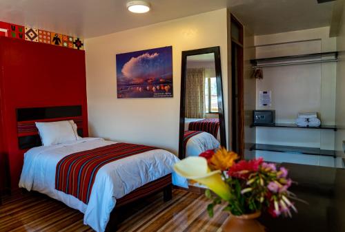 a bedroom with a bed and a mirror and flowers at Hotel Tierra Inka Sacred Valley in Ollantaytambo