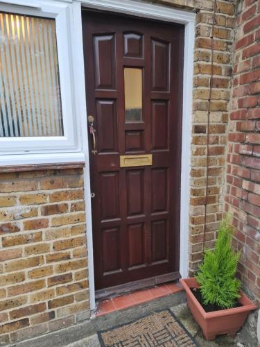 a brown door on a brick building with a plant at Cosy Lodge in Thornton Heath