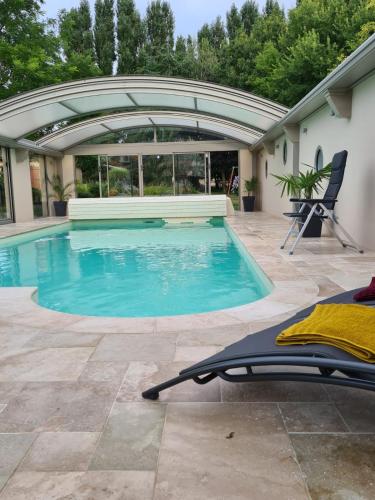 a swimming pool with a patio and a house at La coudraie votre maison de vacances en famille in Daumeray