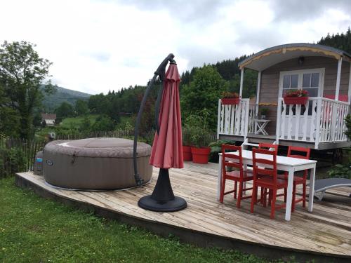 ein Regenschirm auf einem Deck neben einem Whirlpool in der Unterkunft la roulotte arc-en-ciel in Villards-dʼHéria