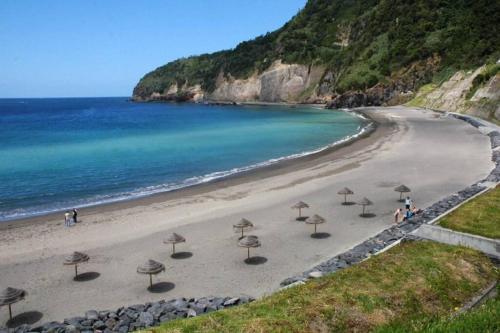 a beach with umbrellas on the sand and the ocean at Apartamento Vista do Mar A in Ribeira Quente