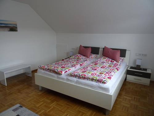 a white bed with pink pillows in a bedroom at Turm im Blick in Dietingen