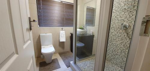 a bathroom with a toilet and a glass shower at Mountain Gem in Bloemfontein