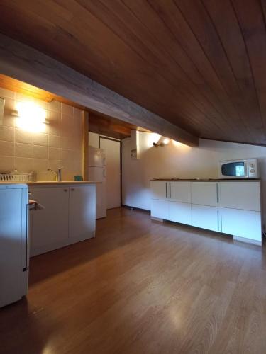 Elle comprend une grande cuisine avec des placards blancs et un plafond en bois. dans l'établissement Logement mansardé dans maison avec jardin en bord de piste, vue montagne, aux Houches