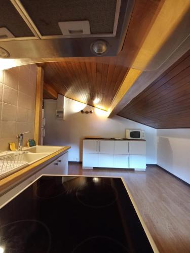 une cuisine avec des armoires blanches et un plafond en bois dans l'établissement Logement mansardé dans maison avec jardin en bord de piste, vue montagne, aux Houches