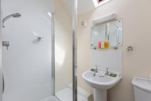a white bathroom with a shower and a sink at The Royal Oak in Gillamoor